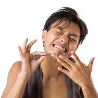 毛抜きで髭を抜く痛みに顔をしかめる男性の自己処理の写真
