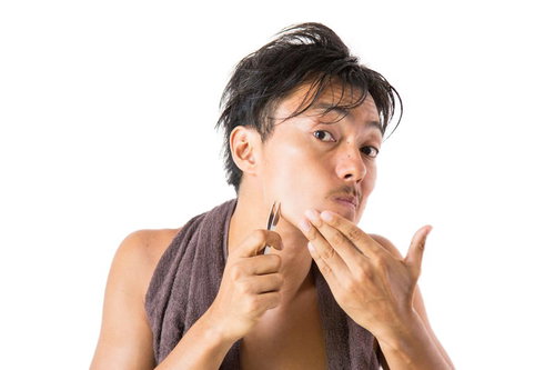 毛抜きで髭の抜き残しを気にして処理する男性