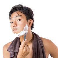 シェービングフォームを使って髭剃りをする男性の写真