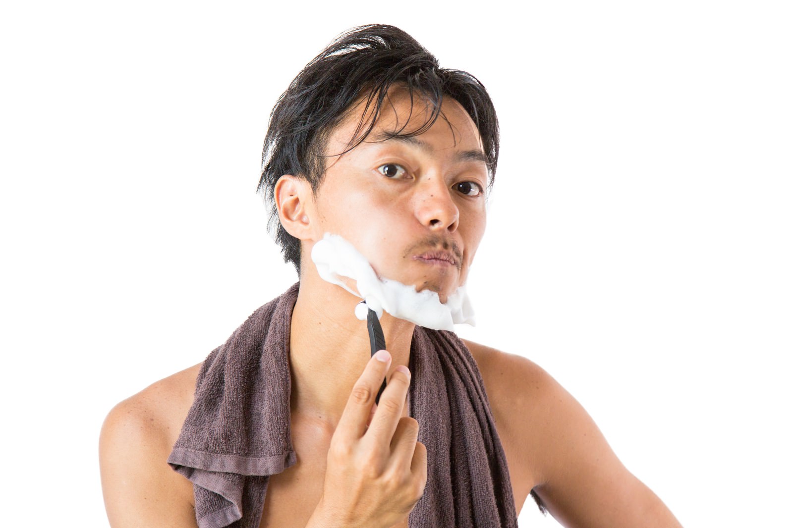 頬を膨らませてカミソリで髭剃りをしている男性［モデル：藤沢篤］