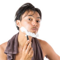 頬を膨らましながらカミソリで髭を剃る男性の写真