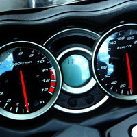 赤い針が指す車のスピードメーターとタコメーターの写真