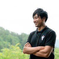 腕を組みながら笑顔で教えるゴルフインストラクターの写真