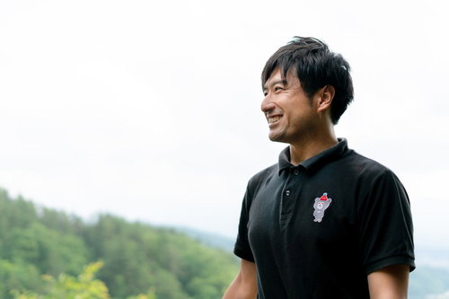 自然に囲まれて爽やかな笑顔を見せる男性インストラクター