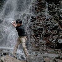 悪いライでも絶対に打っていくゴルファー、滝の岩場でスイングの写真