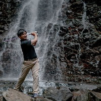 滝が流れる岩場からのゴルフショットの写真