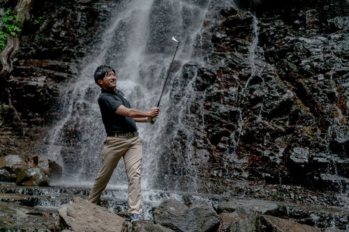 滝と岩場の悪条件下でもゴルフを楽しむゴルファーのインパクト