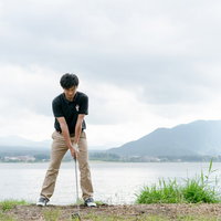 ゴルフ場でクラブを下に置いた正しいアドレスを取るゴルファーの写真