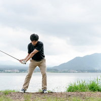 湖畔でスコアが伸びるゴルファーのスイングの写真