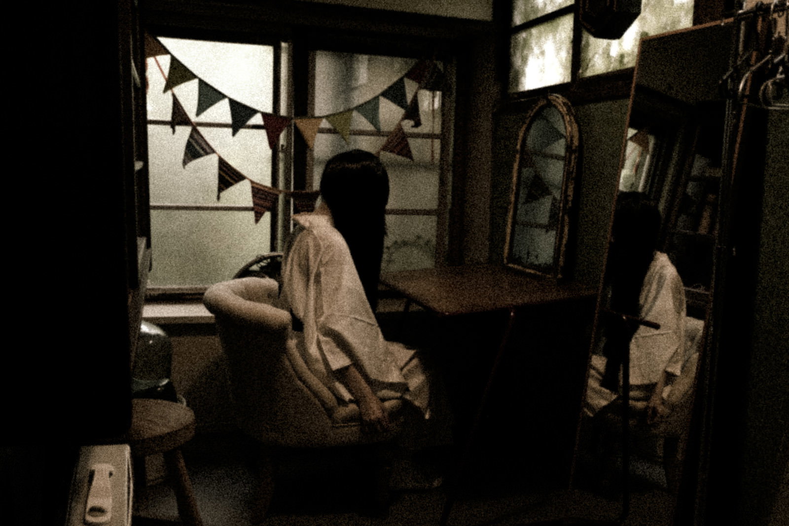 薄暗い古民家の和室で鏡の前に座り白装束に着替える女性［モデル：緋真煉］