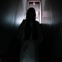 薄暗い階段を降りてくる和女のシルエット、暗闇に浮かぶ不気味な人影の写真
