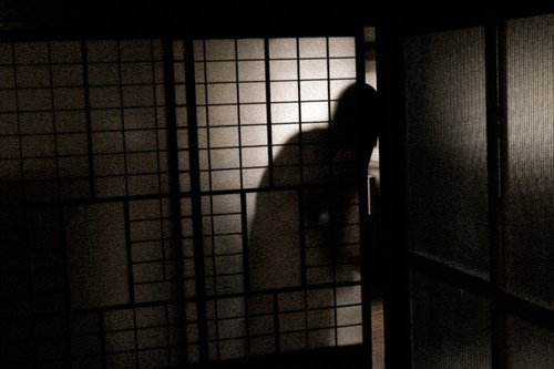 暗い室内の格子窓から覗く女性の人影シルエット