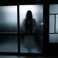 磨りガラスにうっすら映る女性のシルエットの写真