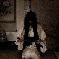 薄暗い和室で小刀を握りしめる白装束の女性の写真