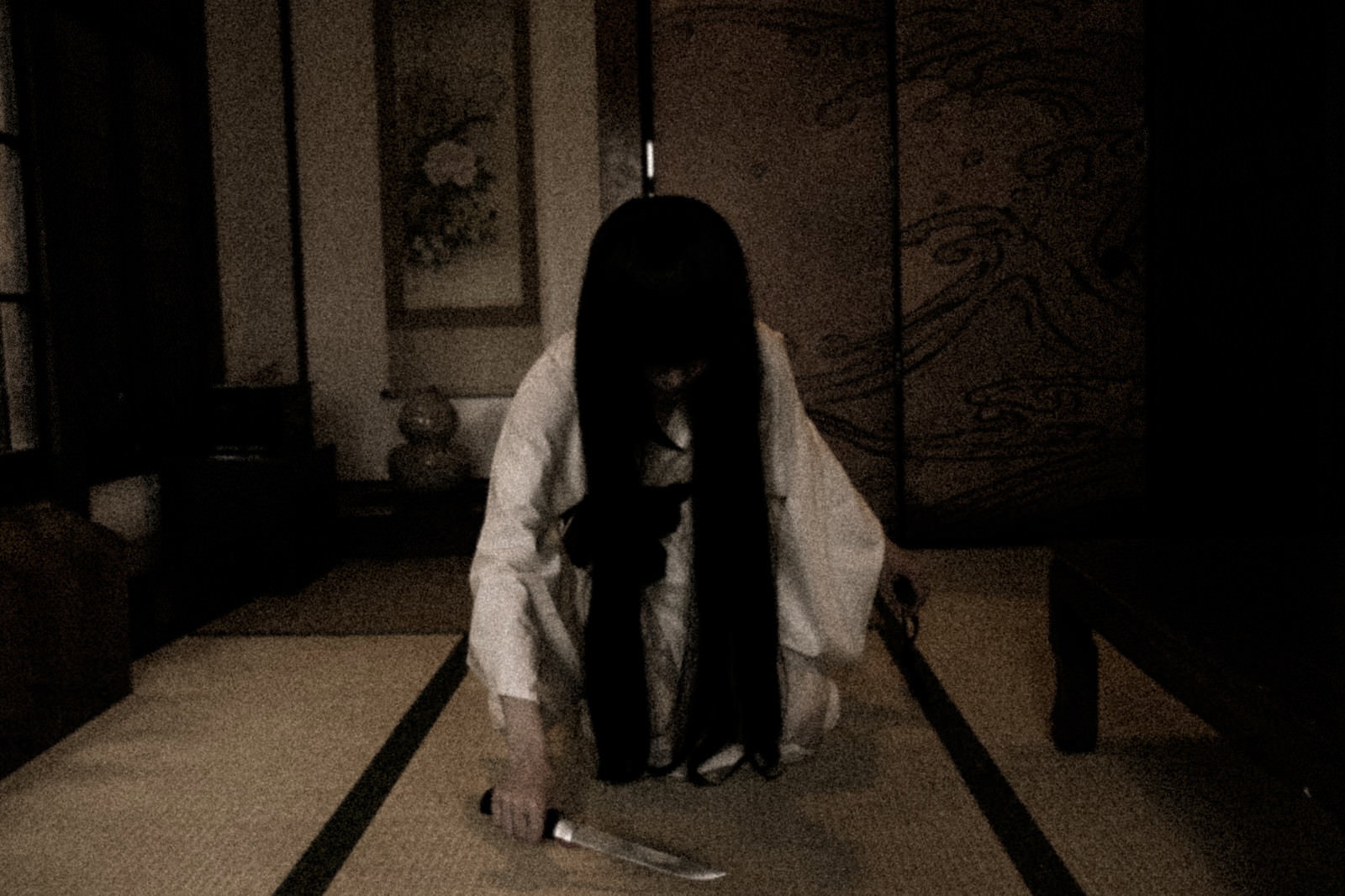 白い着物を着た女性が和室で刃物を持ち座り込んでいる様子［モデル：緋真煉］