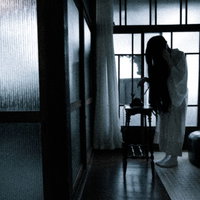 薄暗い室内で呪いの電話をかける女性の後ろ姿の写真