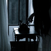 暗い室内で黒電話のダイヤルを回す不気味な女性の姿の写真