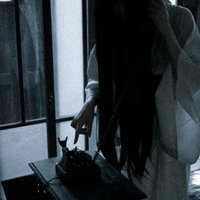 薄暗い部屋で呪いの黒電話を手に取る女性のシルエットの写真