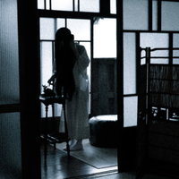 非通知着信アリ、暗い室内で黒電話の前に立つ女性のシルエットの写真