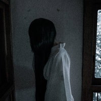 黒髪長髪の女性が暗い部屋の中を徘徊しているホラーの写真