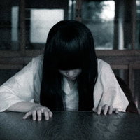 呪ってやると床を這いずる長髪の女性、暗い室内で四つん這いになる怨霊の写真