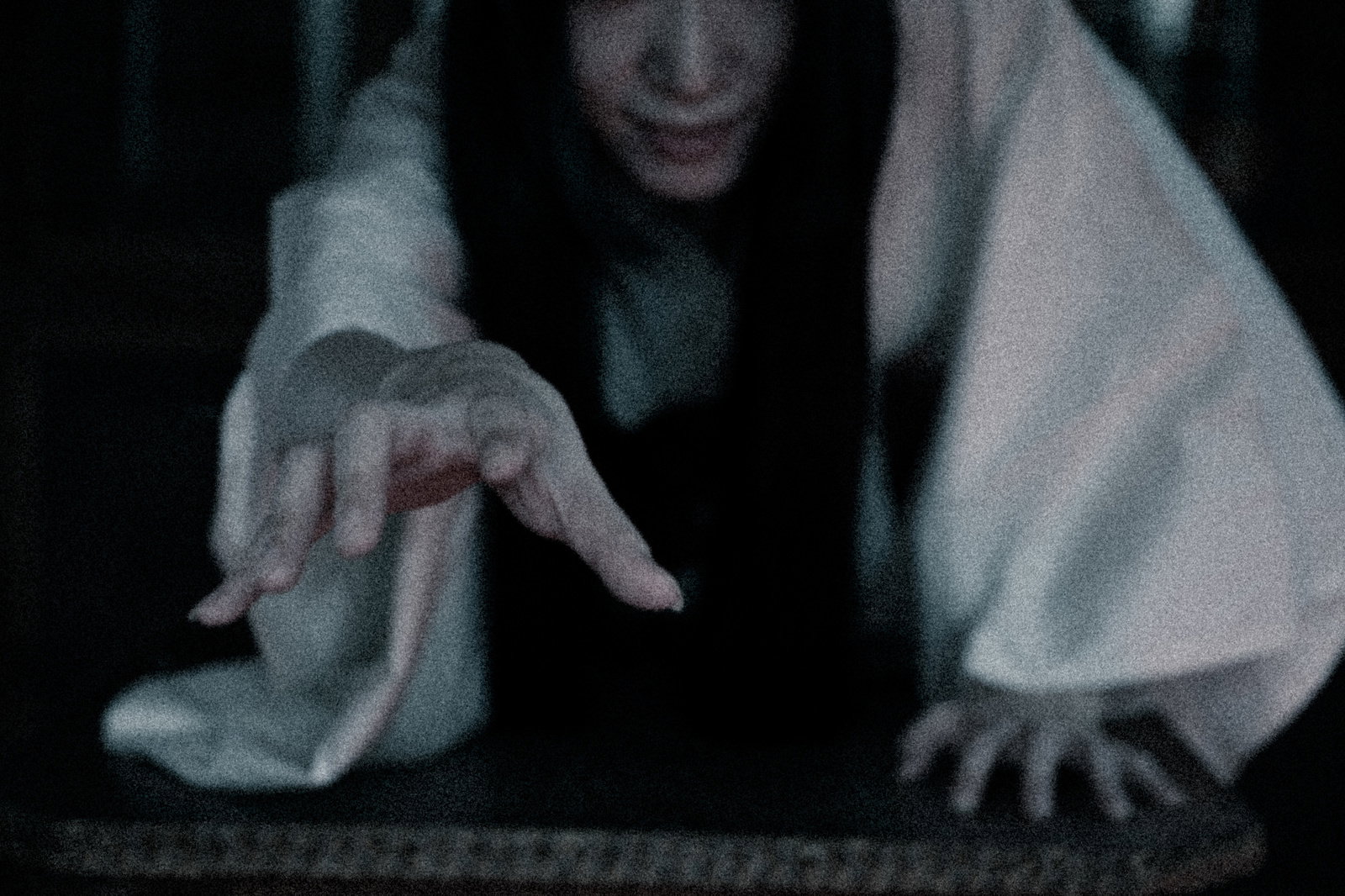 暗い闇の中から白い衣装をまとった長髪の幽霊が両手を伸ばしている［モデル：緋真煉］