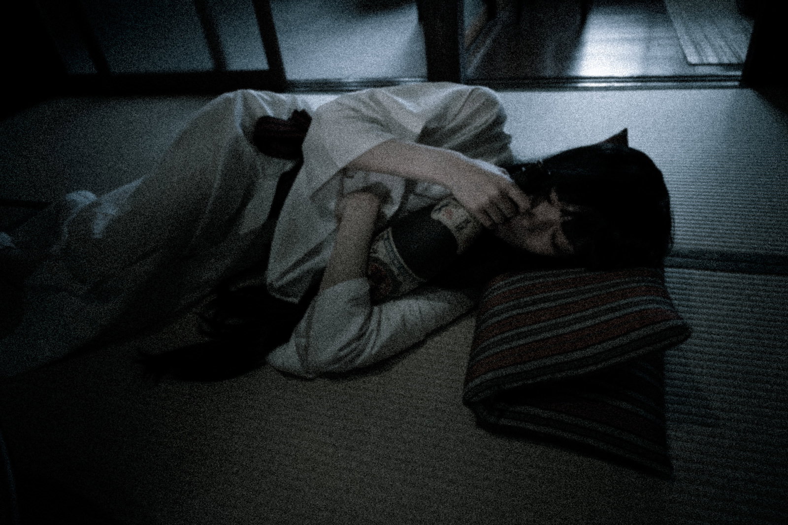 畳の上で白装束を着た女性が一升瓶を抱えて眠っている［モデル：緋真煉］