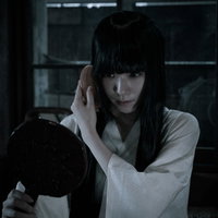 暗がりで髪をとかす不気味な女性の鏡の心霊現象の写真