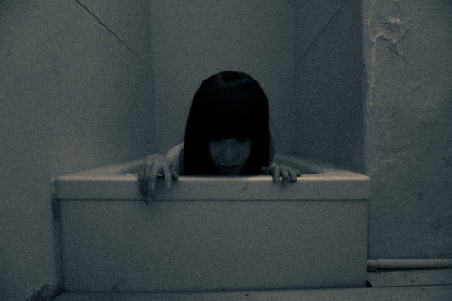 薄暗い浴槽から覗く女性の不気味な姿と怨念の恐怖