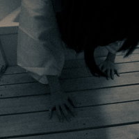 薄暗い空間のすのこの上を這う白い衣装の女性の写真