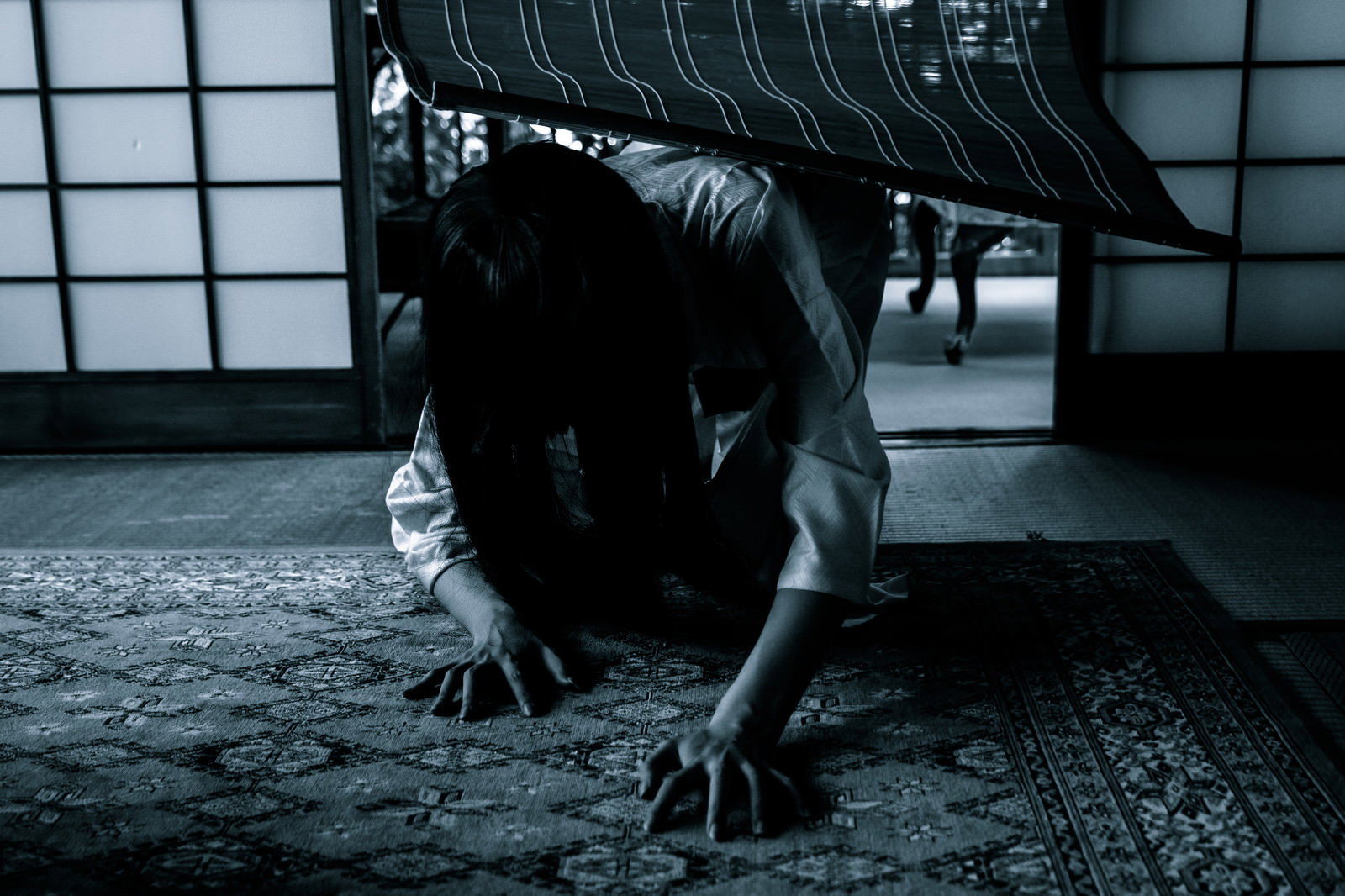 長い黒髪で顔を覆った女性が床を這いつくばっている様子［モデル：緋真煉］