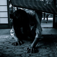 ジリジリ迫りくる恐怖、床を這う黒髪の女性の写真
