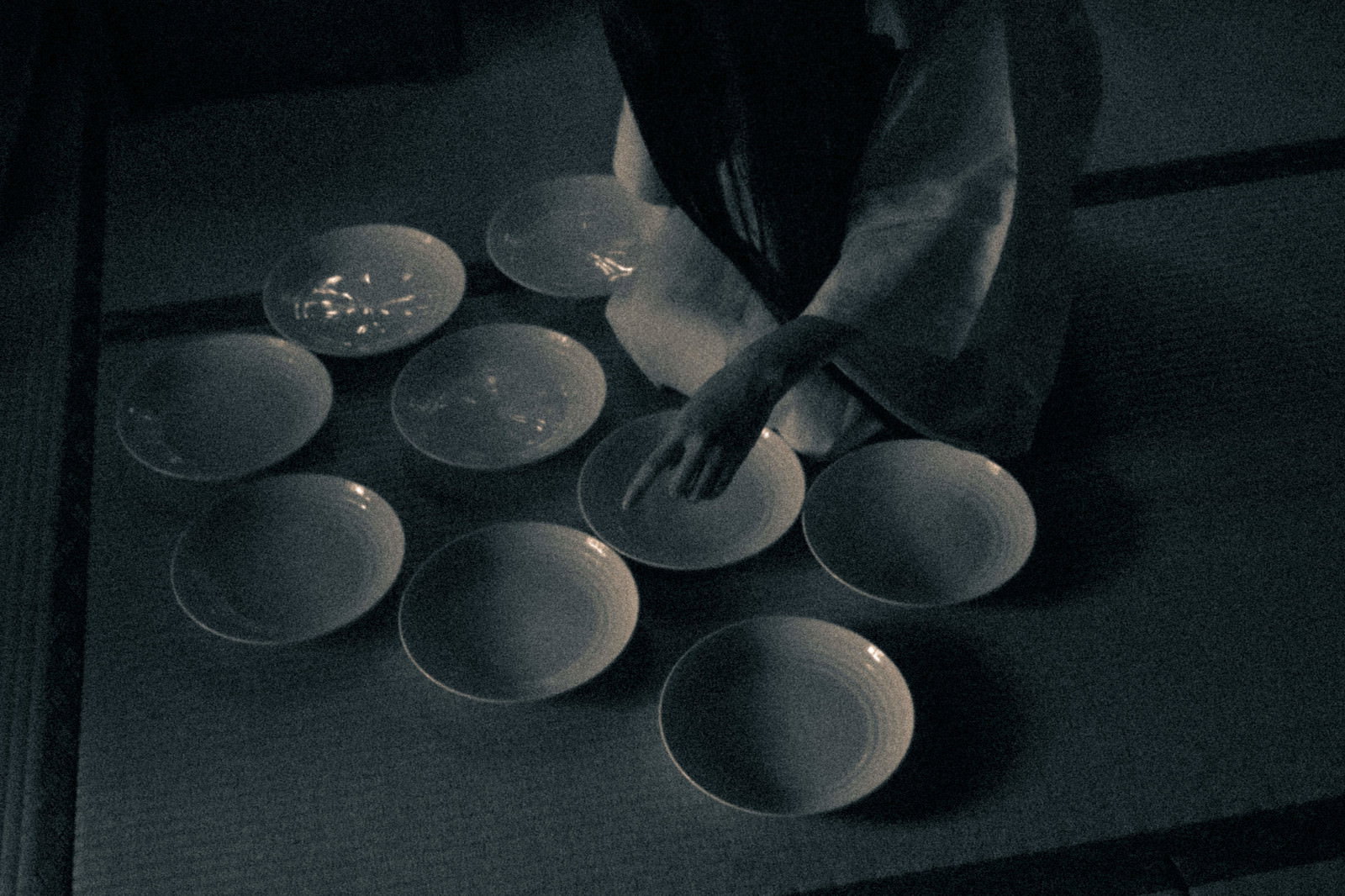 暗闇の中に並んだ白い皿を見下ろすアングルで撮影した不気味な写真［モデル：緋真煉］