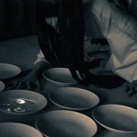 薄暗い空間で皿を見つめる不気味な女性の恐怖表現の写真