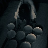 暗がりの中でお皿を並べる不気味なゆうれいのシルエットの写真
