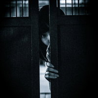 暗闇の扉の隙間からのぞき見る不気味な女性の写真