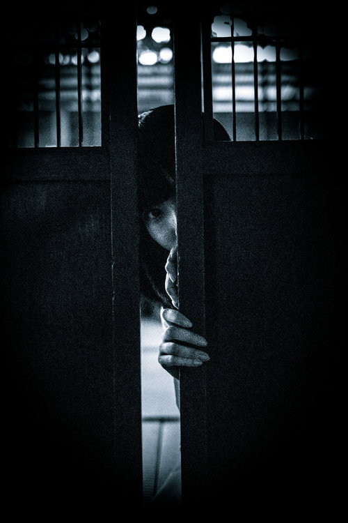 暗闇の扉の隙間からのぞき見る不気味な女性