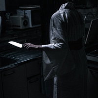 台所に立ち包丁を手にする不気味な女性の表情の写真