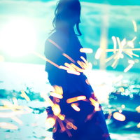 夕暮れの海岸で弾ける火花と佇む女性のシルエットの写真