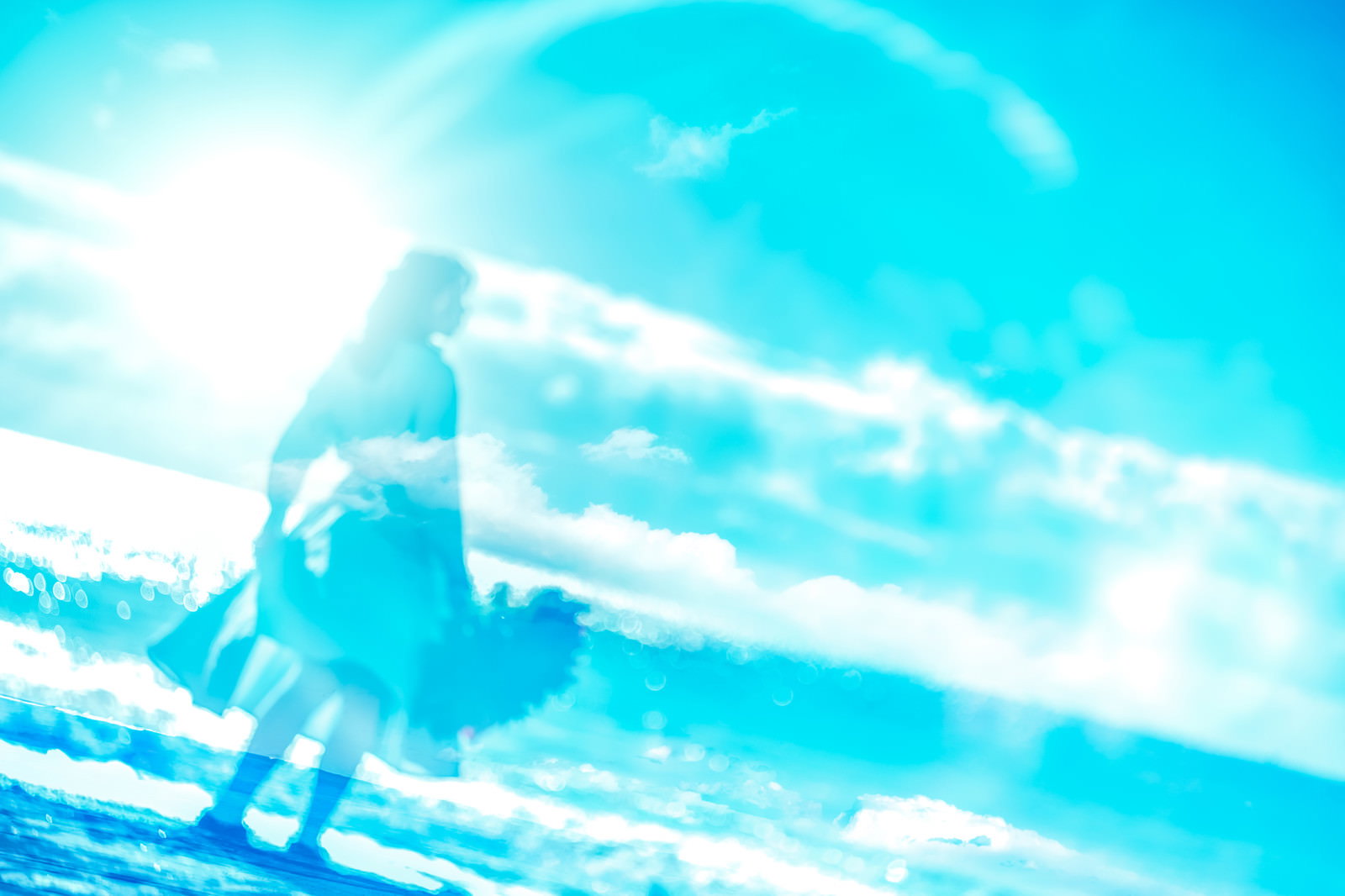 青空と雲を背景に逆光でシルエットになった女性の後ろ姿［モデル：Mizuho］