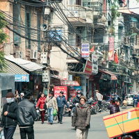 ハノイの市街地を歩く人々が行き交う商店街の通りの写真