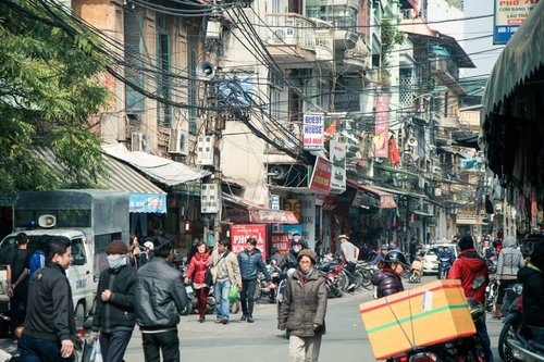 ハノイの市街地を歩く人々が行き交う商店街の通り