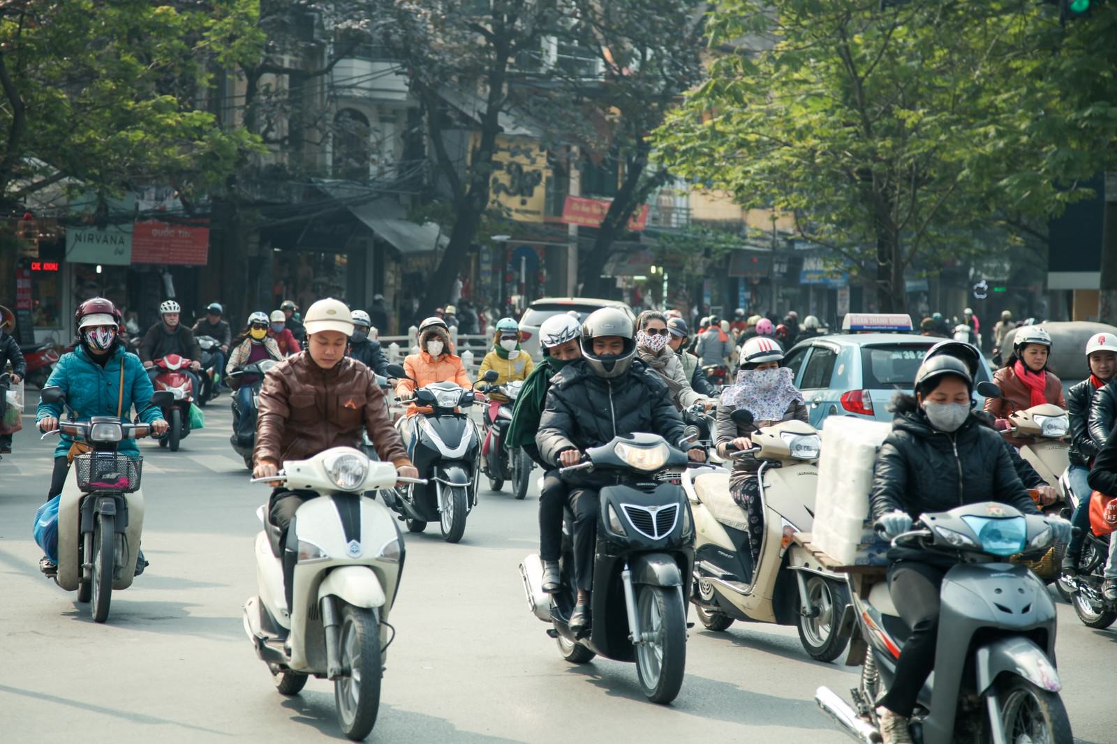 ベトナムハノイの市街地でヘルメットを着用した多数のバイク運転手が道路を走行している様子