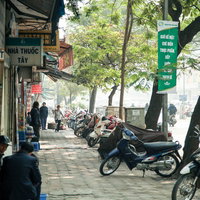ハノイ市街の歩道に並ぶバイクと街路樹の通りの写真
