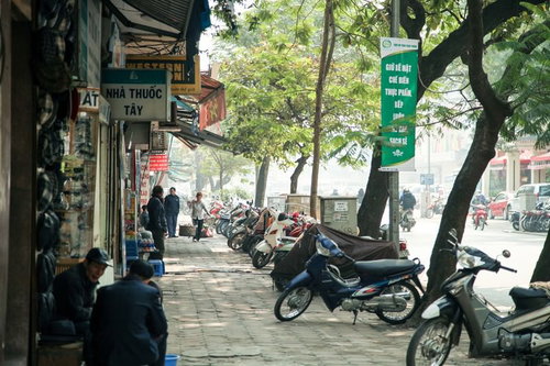 ハノイ市街の歩道に並ぶバイクと街路樹の通り