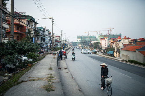 ハノイ郊外の街並みとバイク、歩行者が行き交う日常風景