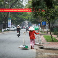 ベトナムの市街地で天秤棒を担ぐ女性の日常風景の写真