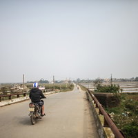 フエ（ベトナム）の田舎道の橋を走行するバイクの写真