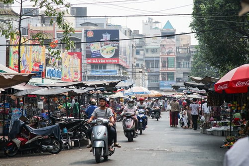 ホーチミンの活気あるマーケット街を走行するバイクと人混み