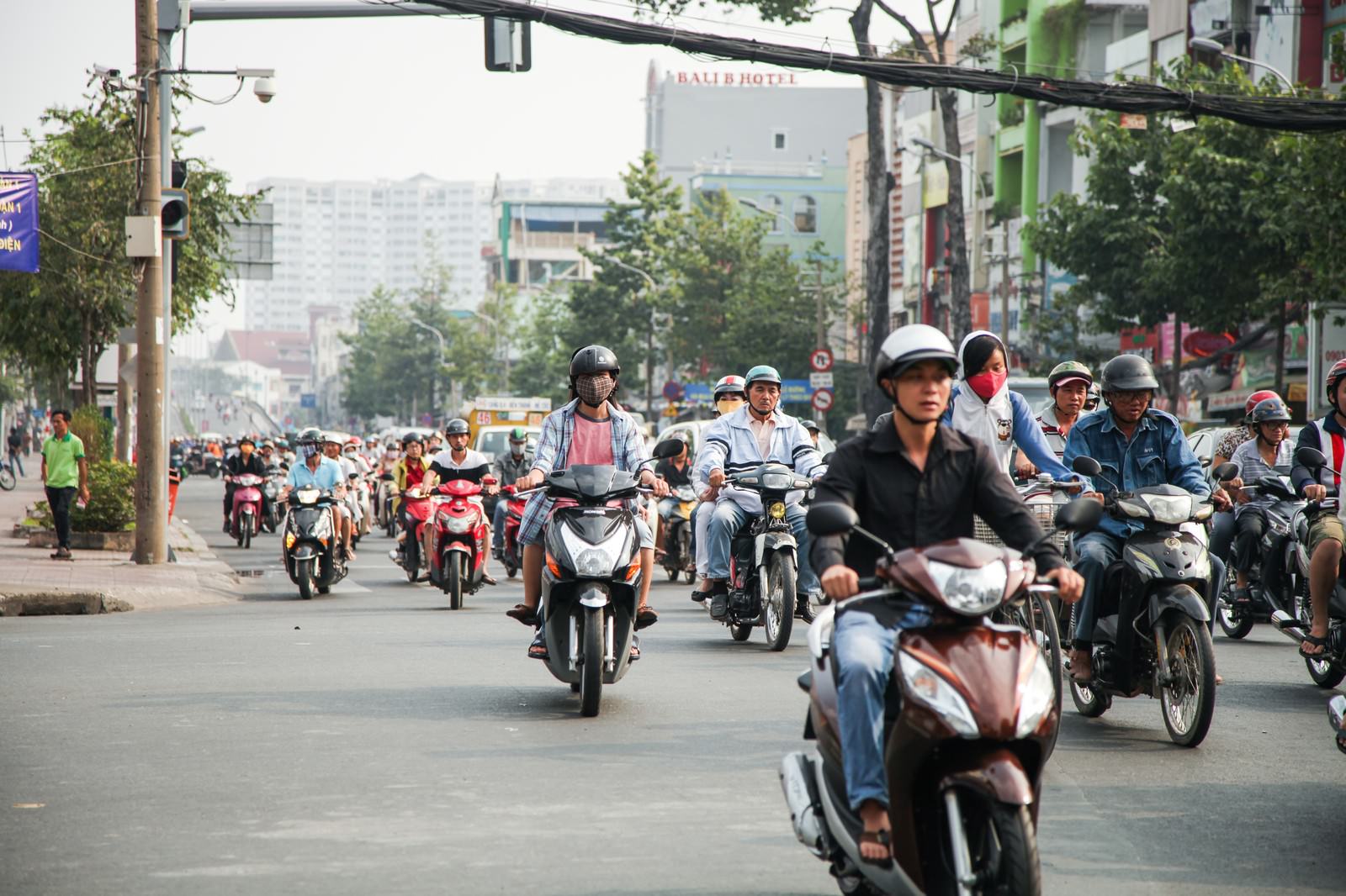 ベトナムの市街地で多数のバイクが道路を走行している様子